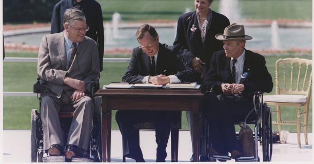 President George Bush signs into law the Americans with Disabilities Act of 1990 on the South Lawn of the White House.