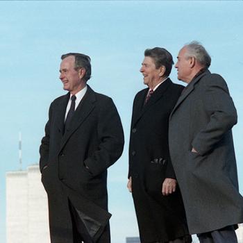 President-Elect Bush, President Reagan, and President Gorbachev stand outside with skyscraper buildings in the background
