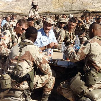 President Bush is seated at a table surrounded by members of the military