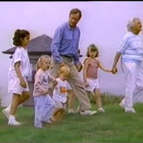 George Bush walking through grass hand-in-hand with his family