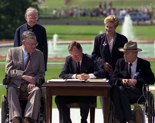 President Bush is seated at a table on the White House lawn signing a document