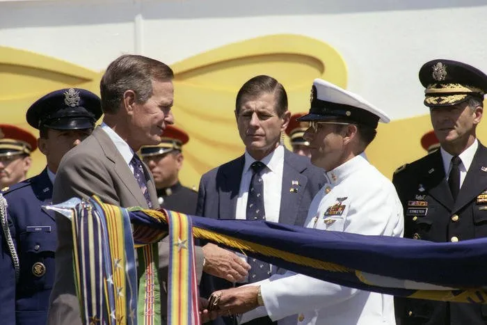 The President prepares to present Operation Desert Storm battle streamers to Navy with the assistance of the Secretary of the Navy, H. Lawrence Garrett, III, Navy Chief of Staff Admiral Frank B. Kelso, and Master Chief Petty Officer Duane R. Bushey