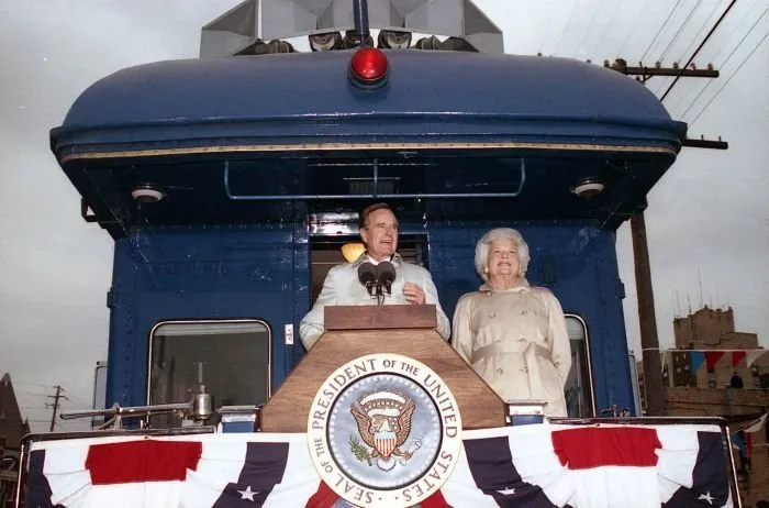 President Bush addresses supporters in Oshkosh, WI as Barbara Bush looks on
