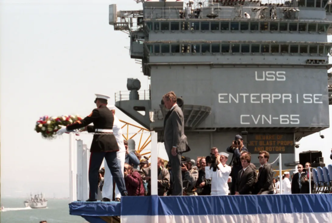 Vice President Bush looks on as a sailor and a marine as they prepare to throw a wreath from the USS Enterprise in San Francisco Bay during the "Peace in the Pacific" ceremony marking the 40th Anniversary of VJ Day