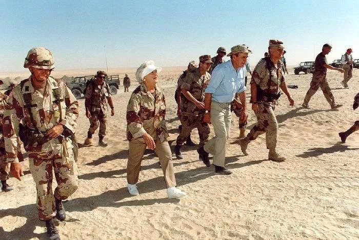 President Bush and Barbara Bush walk in desert in Saudi Arabia with General Scharzkopf