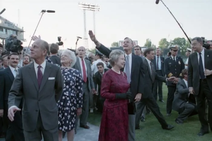President Bush,  Queen Elizabeth II, Prince Philip, and Barbara Bush wave to the crowd at Memorial Stadium