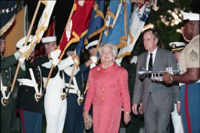 President and Mrs. Bush walk past the joint service color guard during a ceremony commemorating the 50th anniversary of the Japanese attack on Pearl Harbor, held at the National Memorial Cemetery of the Pacific.
