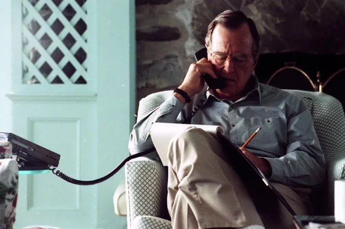 President Bush speaks to Turkish President Turgut Ozal via telephone during a briefing with Robert Gates and Andy Card in the living room of his home in Kennebunkport, Maine