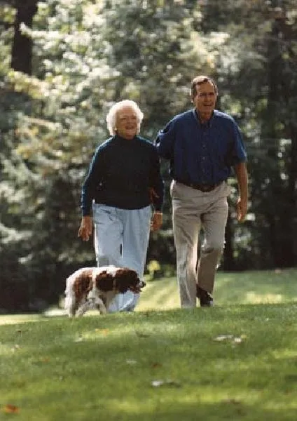 President Bush and Barbara Bush walk with Millie at Camp David