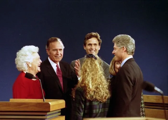 President Bush, Barbara Bush, and Marvin Bush chat with Governor Bill Clinton, Hillary Clinton, and their daughter Chelsea on stage at the third Presidential Debate in East Lansing, Michigan