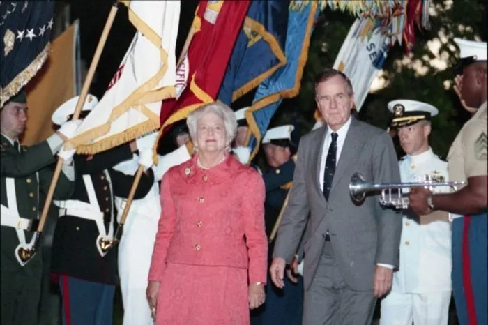 President and Mrs. Bush walk past the joint service color guard during a ceremony commemorating the 50th anniversary of the Japanese attack on Pearl Harbor, held at the National Memorial Cemetery of the Pacific.
