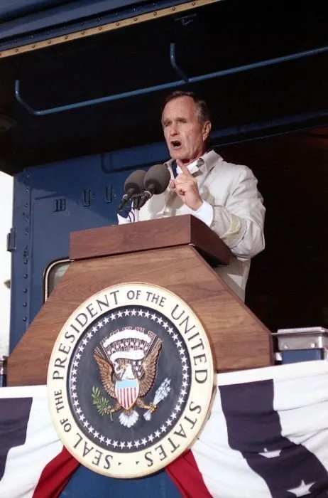 President Bush addresses supporters in Oshkosh, WI as Barbara Bush looks on