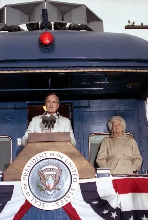 President Bush addresses supporters in Oshkosh, WI as Barbara Bush looks on