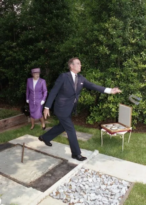 President Bush demonstrates his horseshoe pitching abilities to Queen Elizabeth II