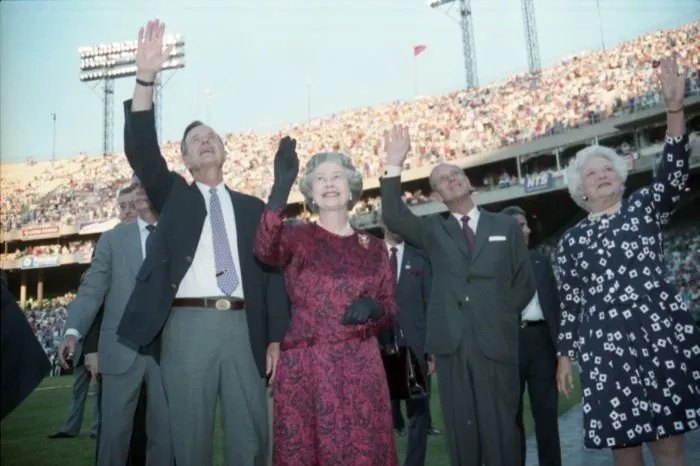 President Bush,  Queen Elizabeth II, Prince Philip, and Barbara Bush wave to the crowd at Memorial Stadium