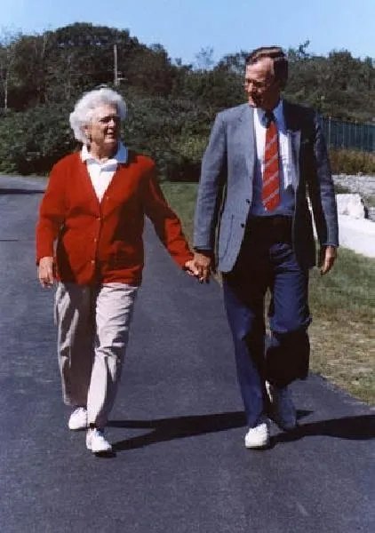 President Bush and Barbara Bush hold hands as they walk down driveway