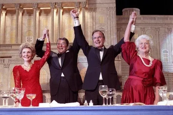 President Ronald Reagan and Vice President George Bush, accompanied by wives Nancy and Barbara, join hands after the President endorses Bushes run for the Presidency during the President's Dinner, Washington, DC