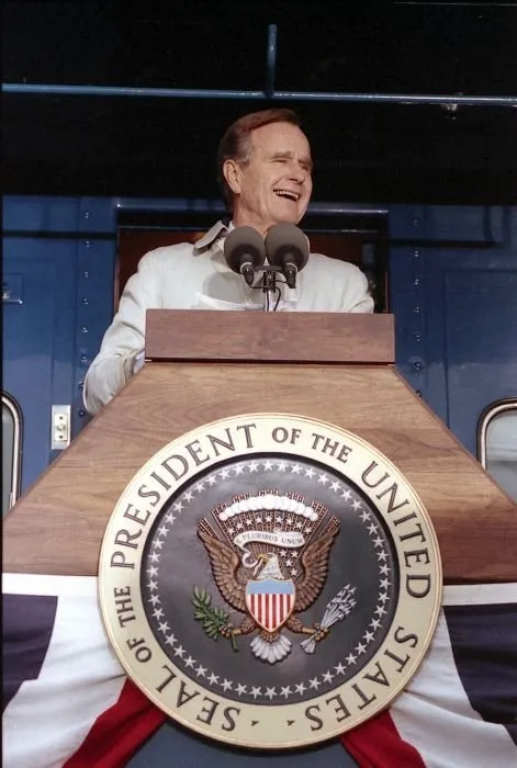 President Bush addresses supporters in Oshkosh, WI as Barbara Bush looks on