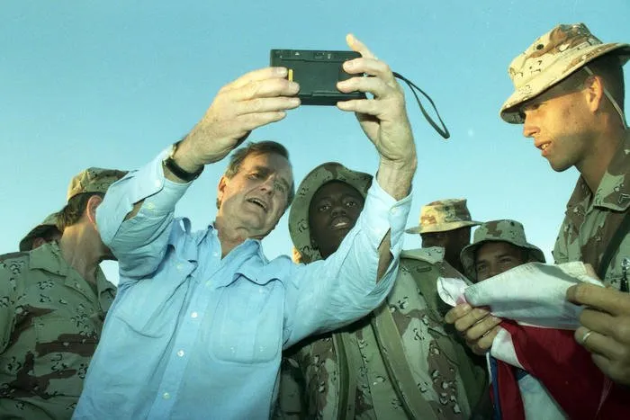 President Bush takes pictures with troops in Saudi Arabia during his Thanksgiving visit